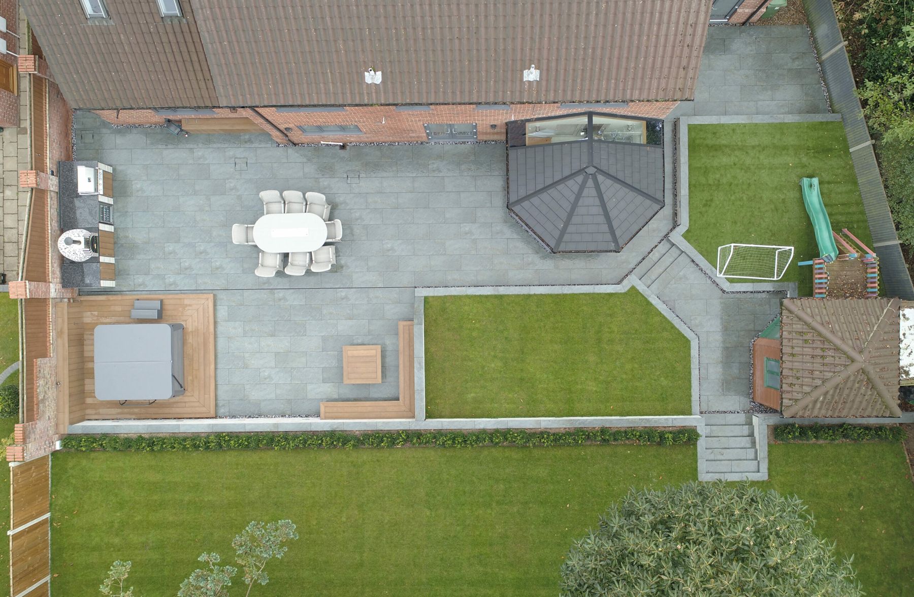 Aerial view of a large garden with a grey patio, gazebo, lawns and a play area