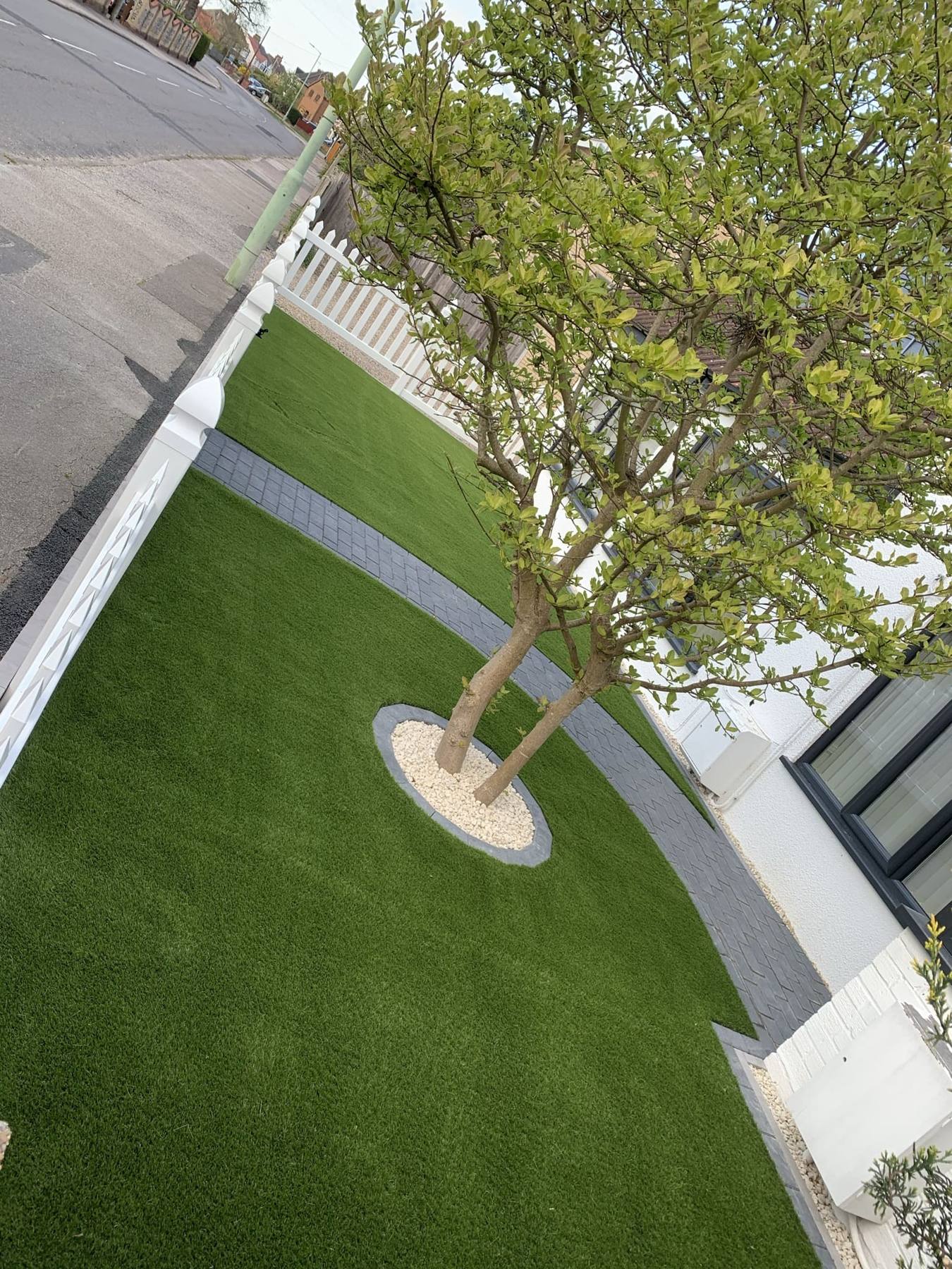 Artificial grass with a curved edge around a tree