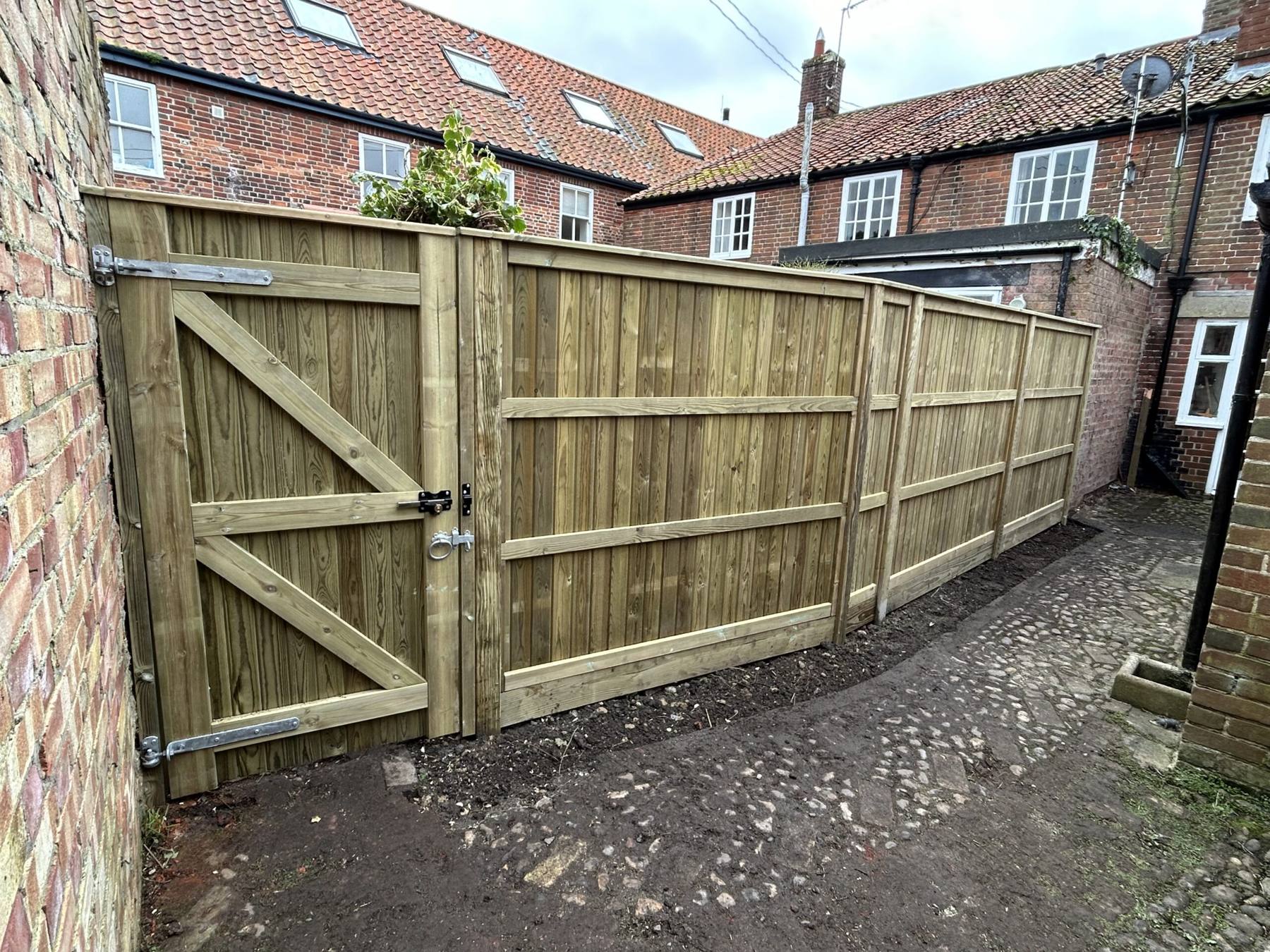 New closeboard timber fence and gate beside cottages