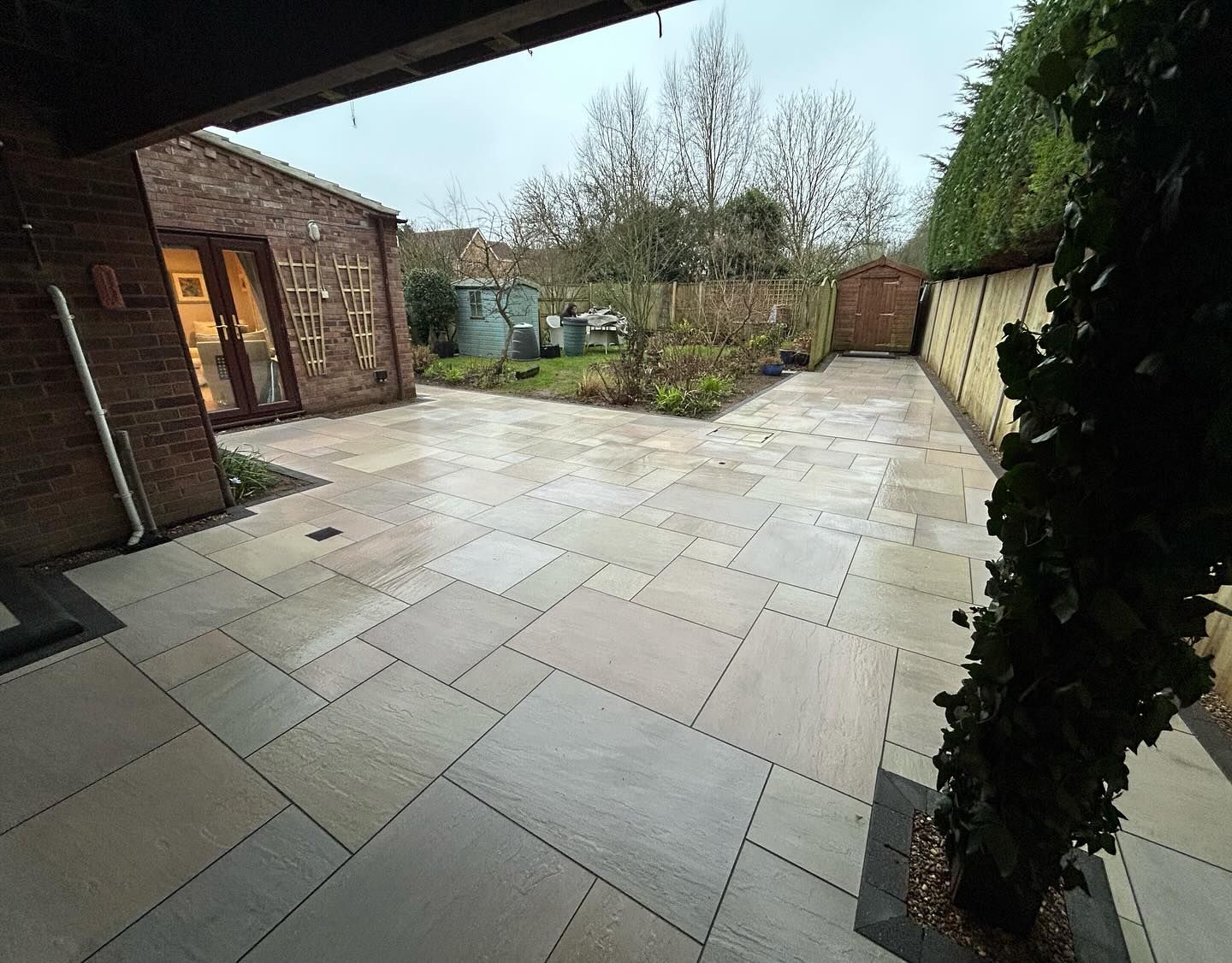 Porcelain patio running from a covered seating area out to the garden