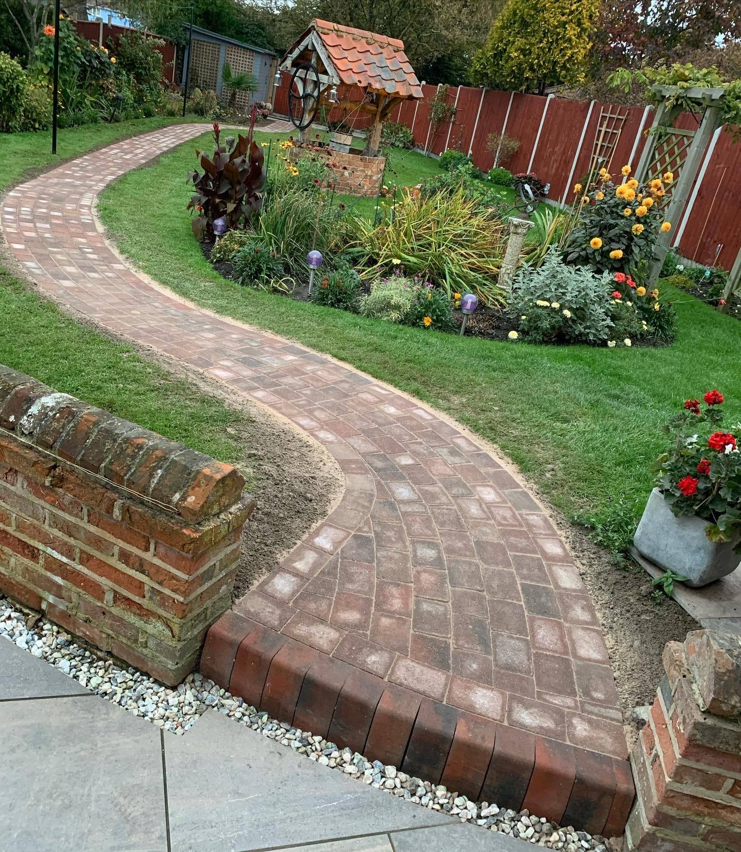 Curving brick-paved path through a lawn and planted borders
