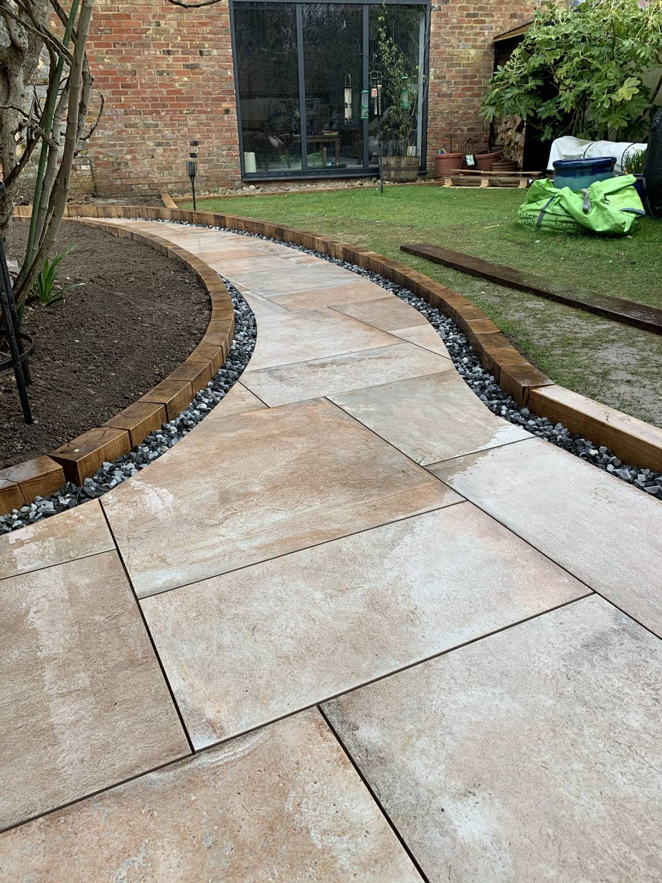 Curving porcelain path edged with timber sleepers