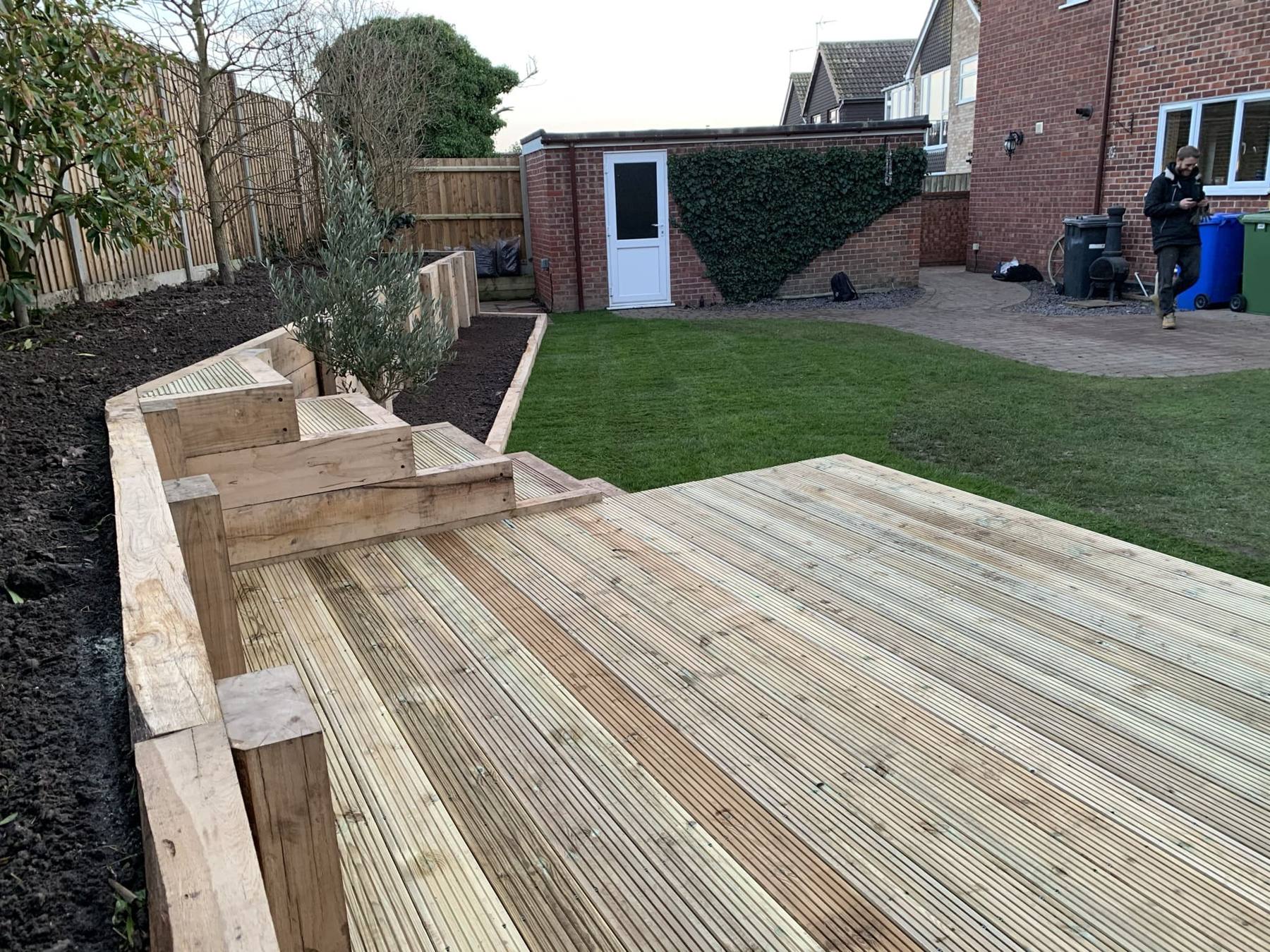 Timber decking with raised sleeper beds and a lawn