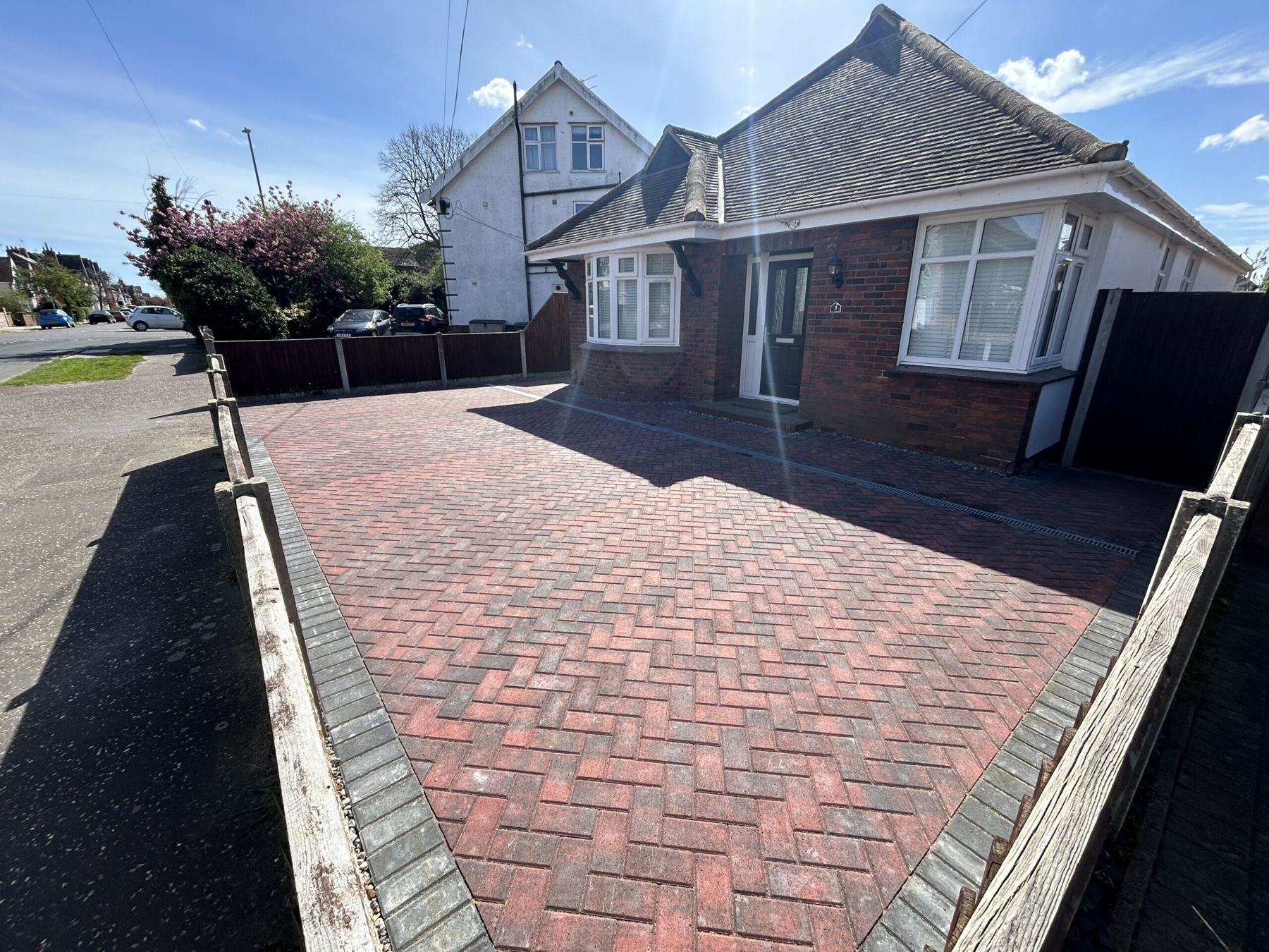 Red herringbone block paved driveway in front of a bungalow