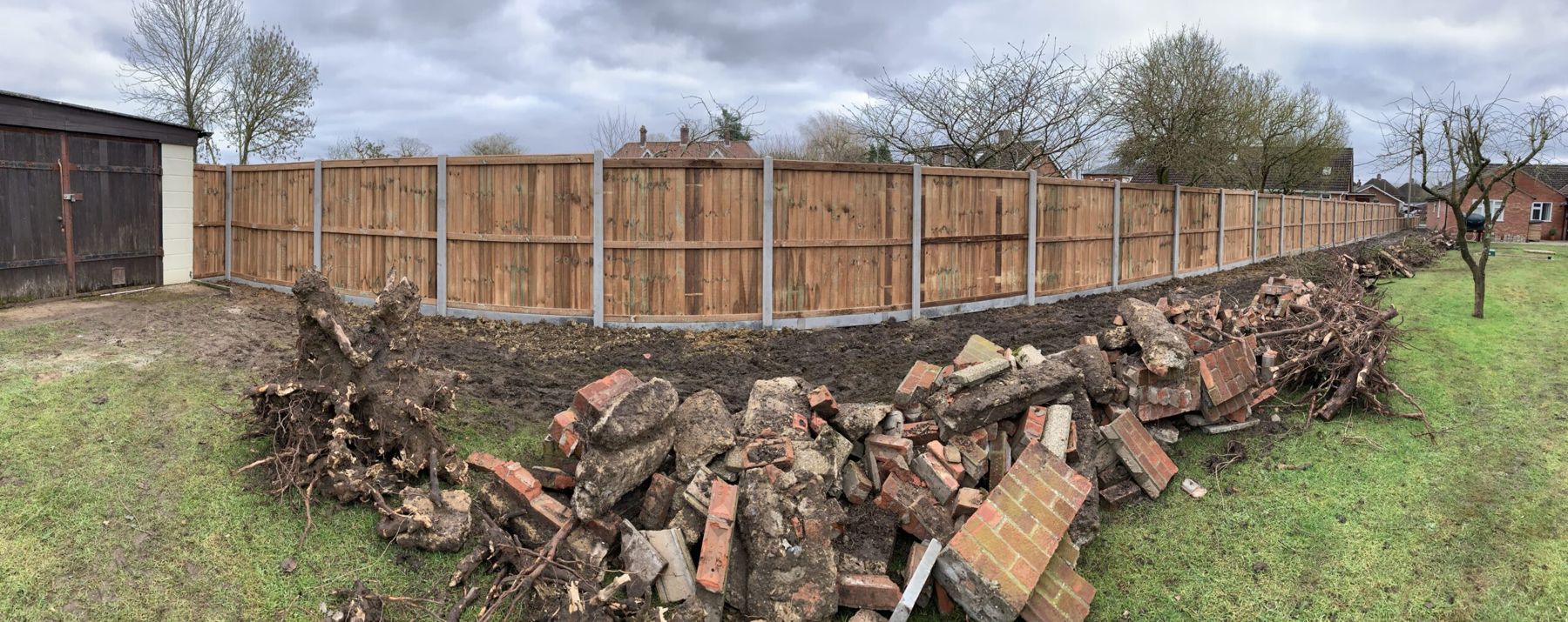 Garden clearance: old bricks and roots piled beside a new fence