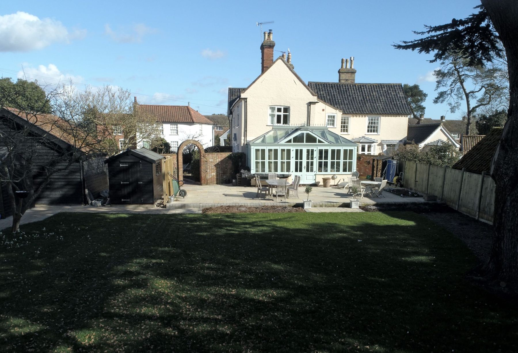 Lawn behind a house with a conservatory