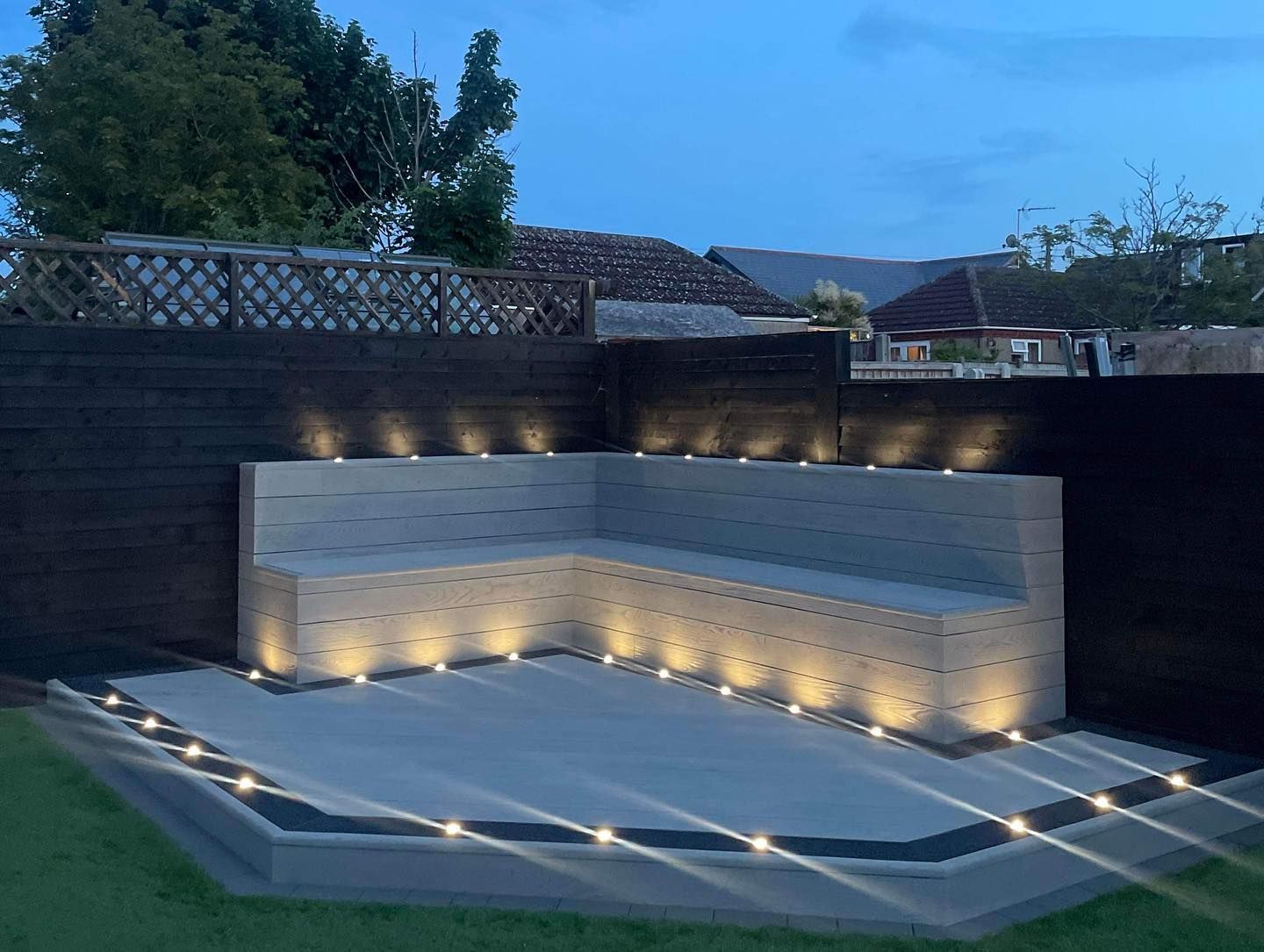 Built-in corner seating and a raised deck lit with low LED lights at dusk