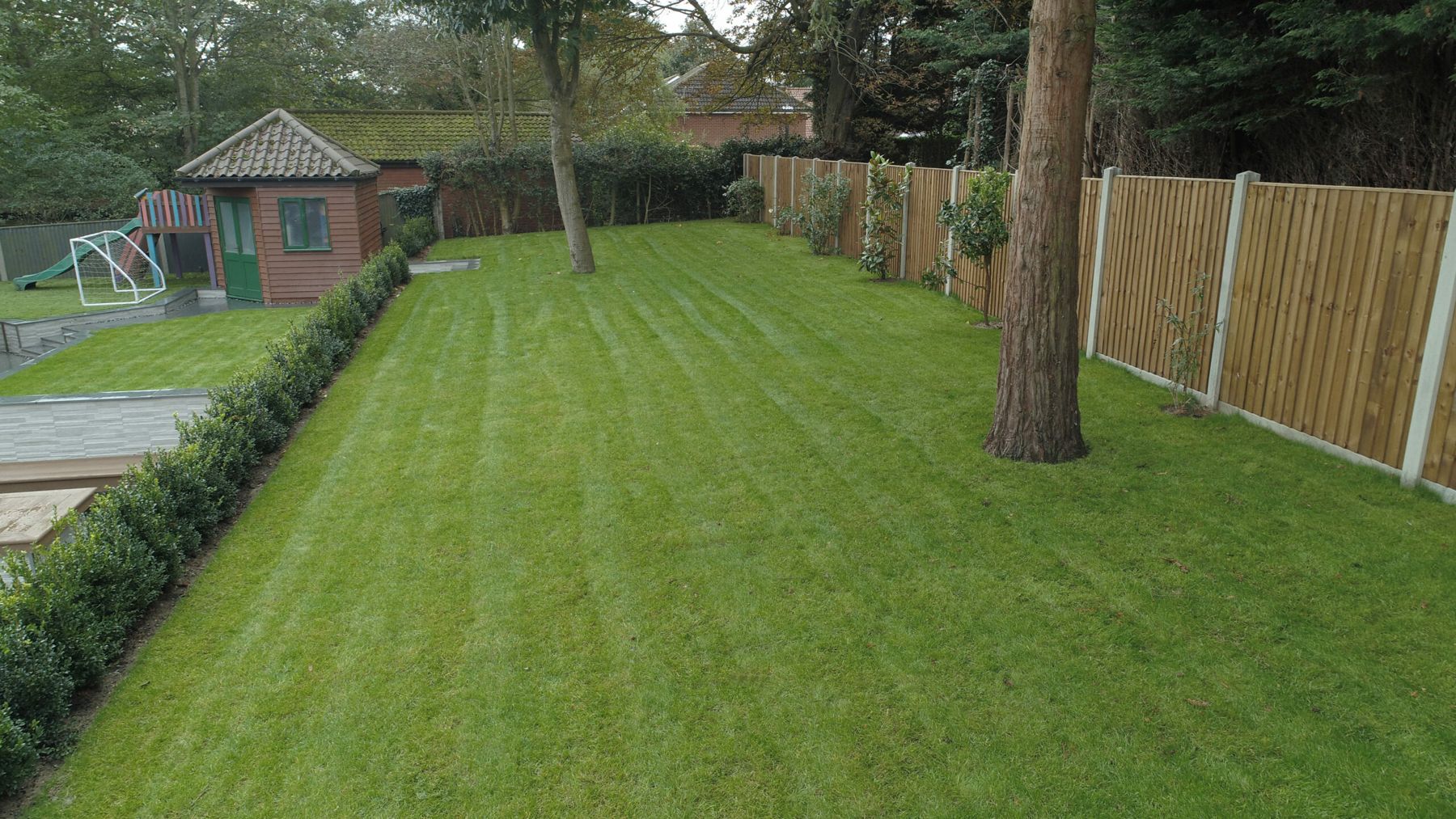 Long striped lawn with timber fencing and mature trees