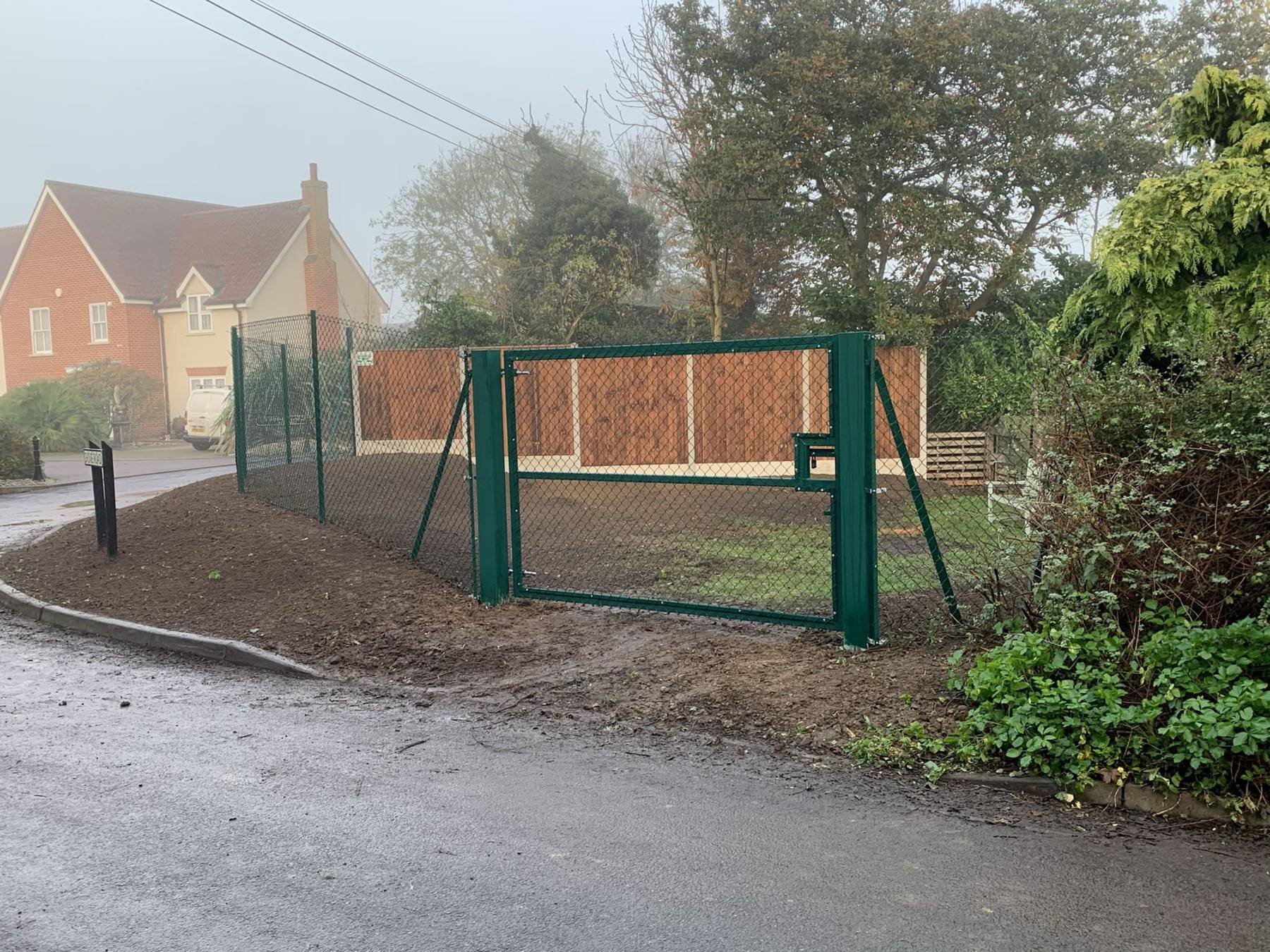 Green mesh security fence and gate at a field entrance