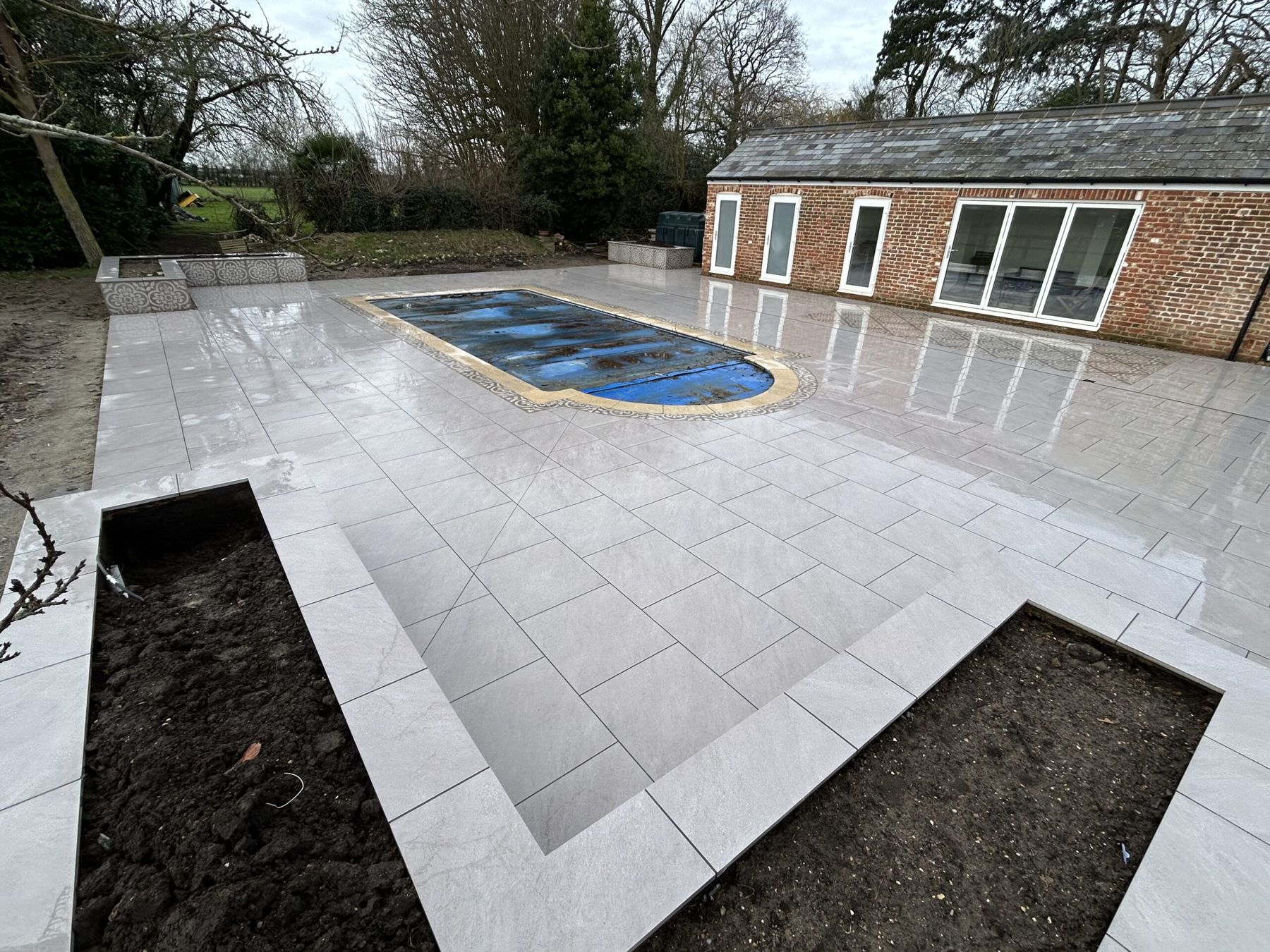 White porcelain patio around a pool with planting beds cut into it