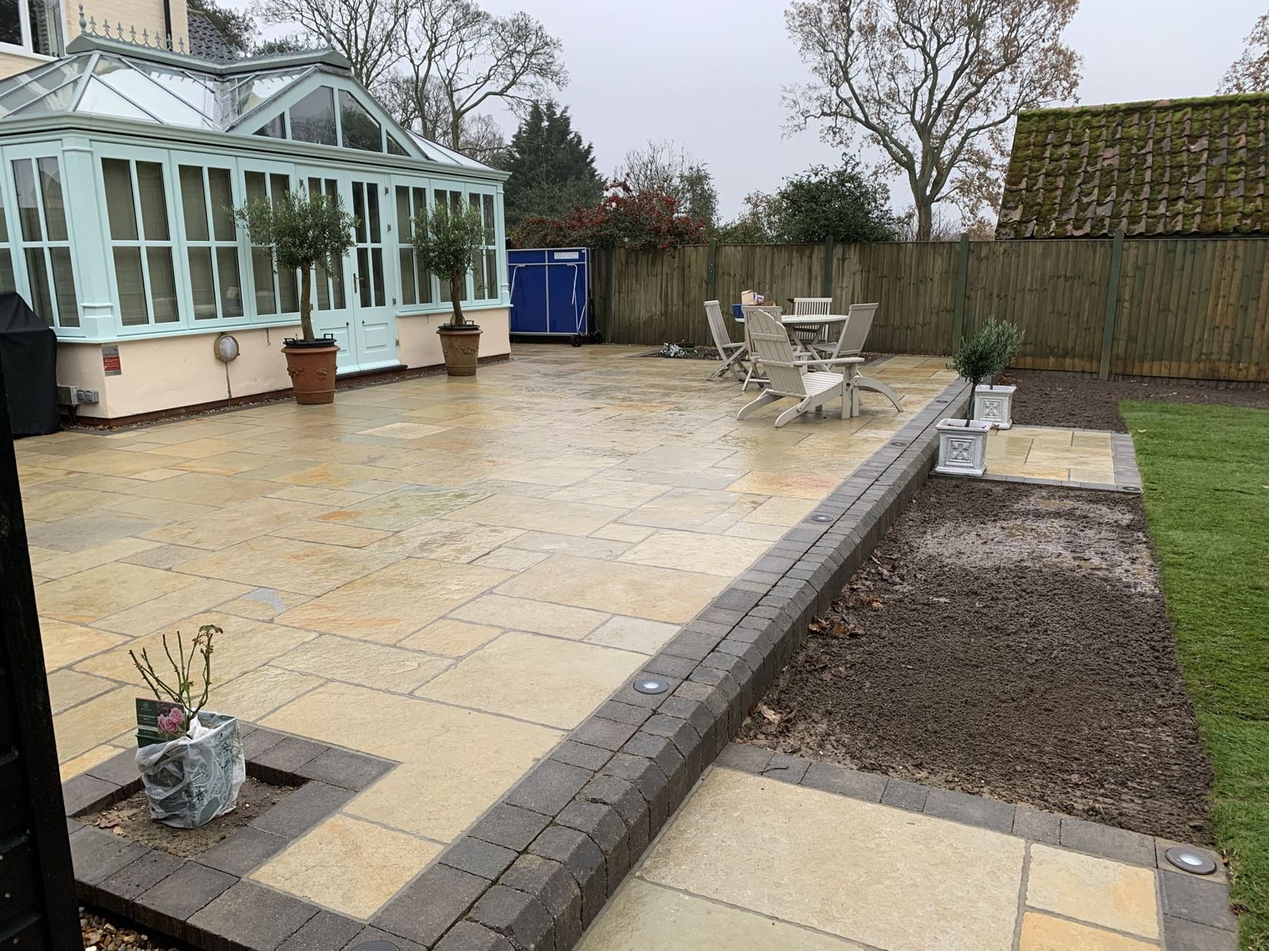 Sandstone patio with a block paving edge next to a planting border