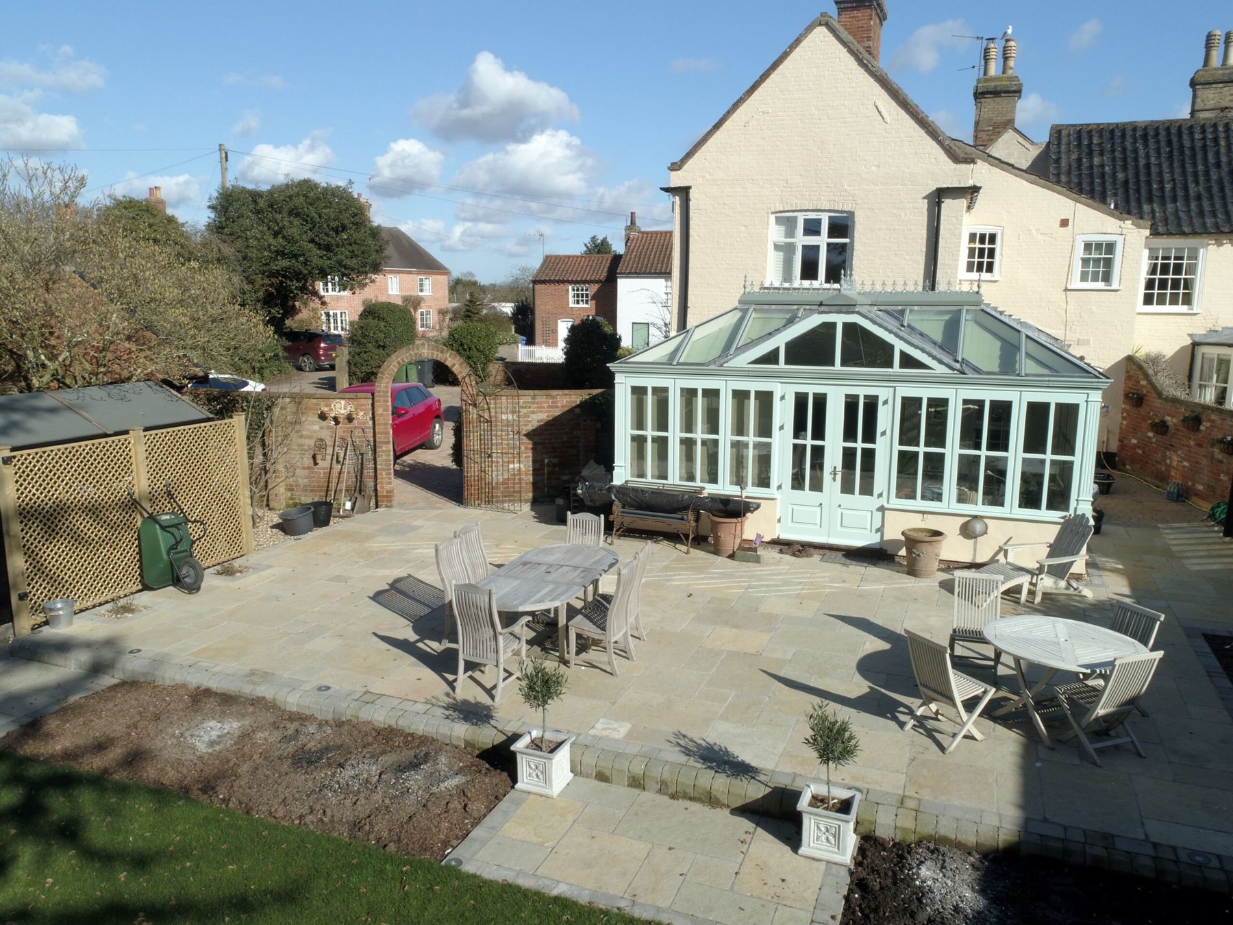 Sandstone patio with garden furniture beside a conservatory