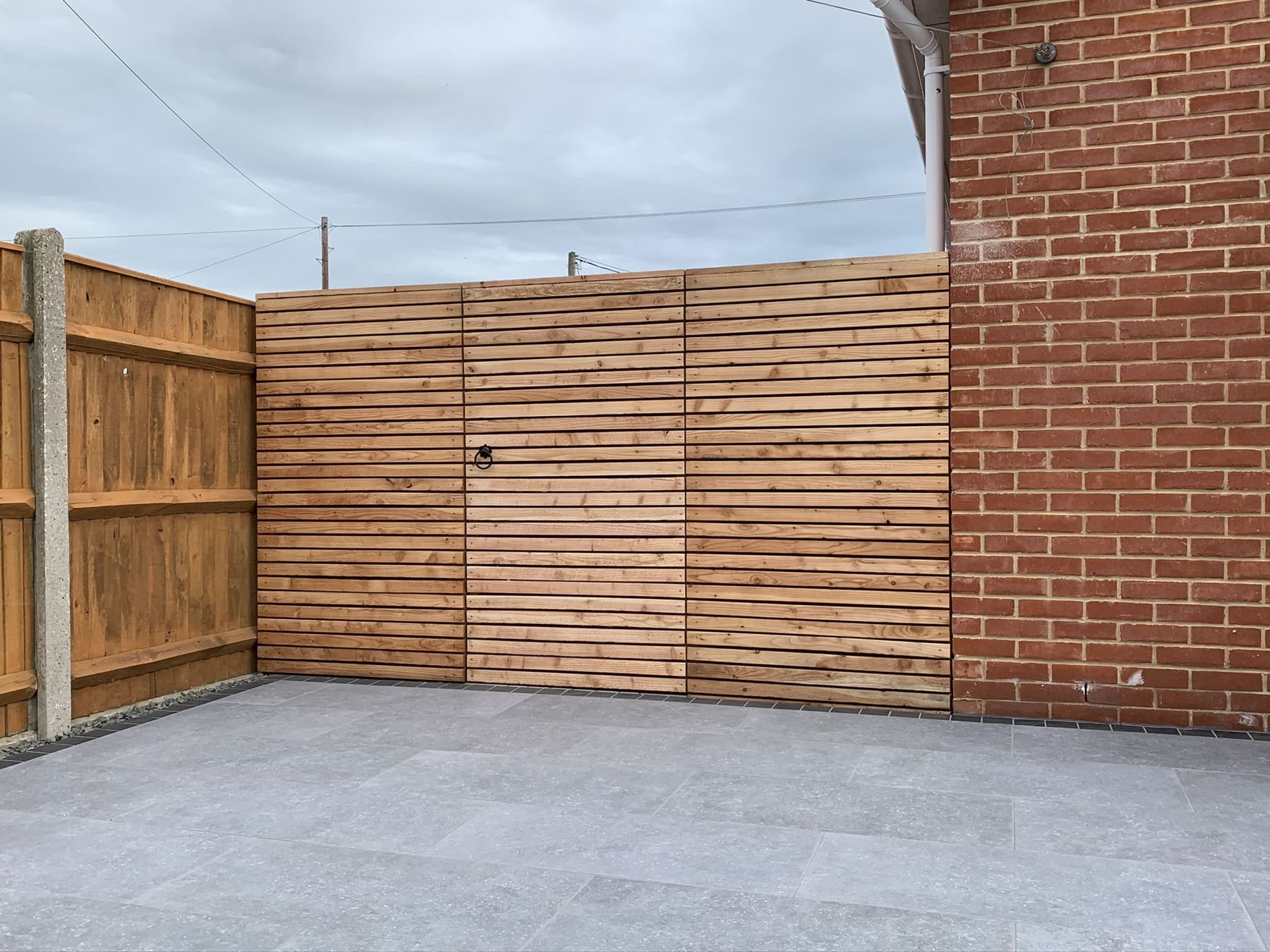 Horizontal slatted fence above a grey porcelain patio