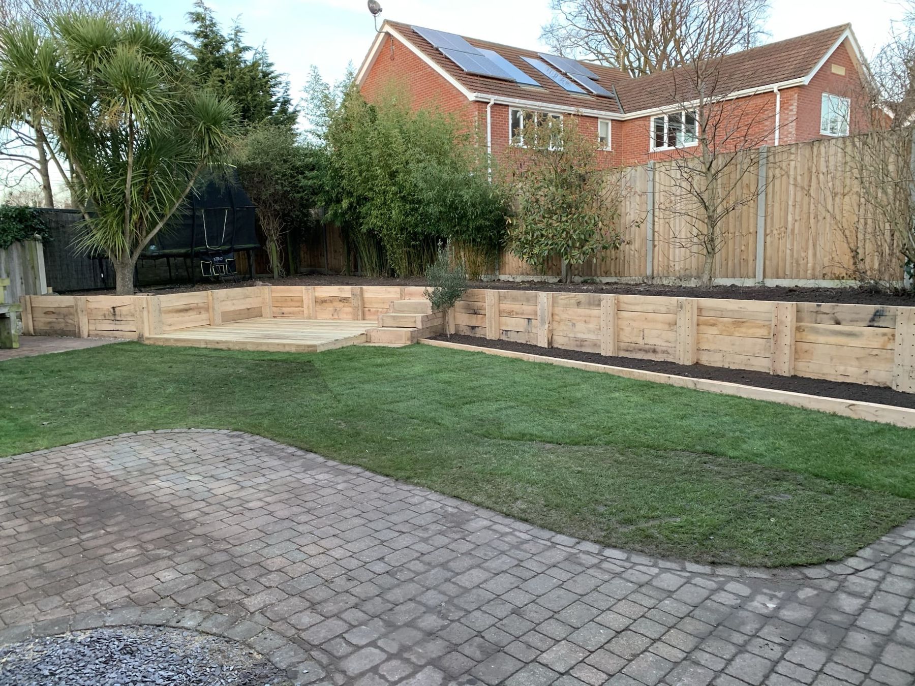 Sleeper raised beds around a lawn above block paving