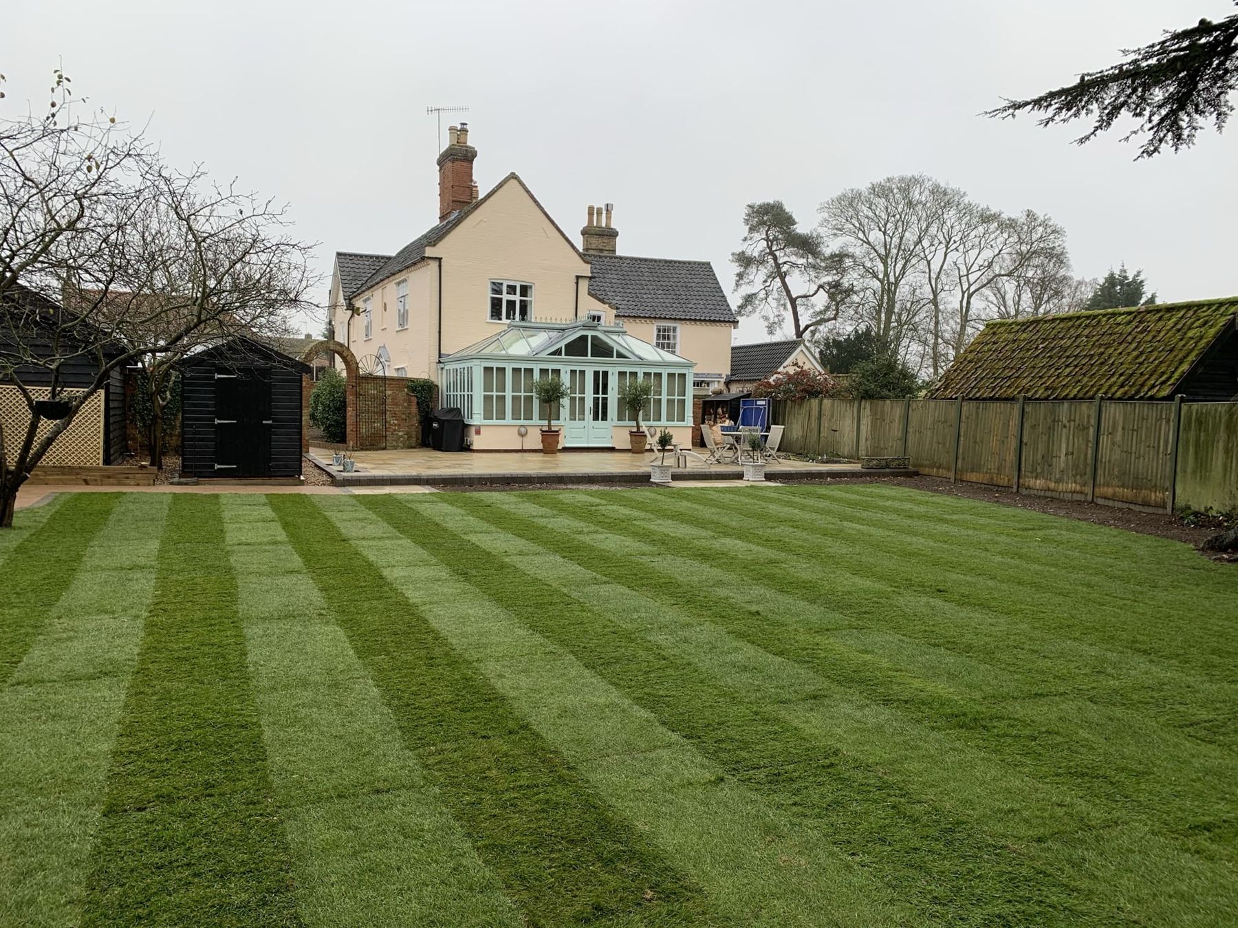 Freshly striped lawn in front of a house with a conservatory