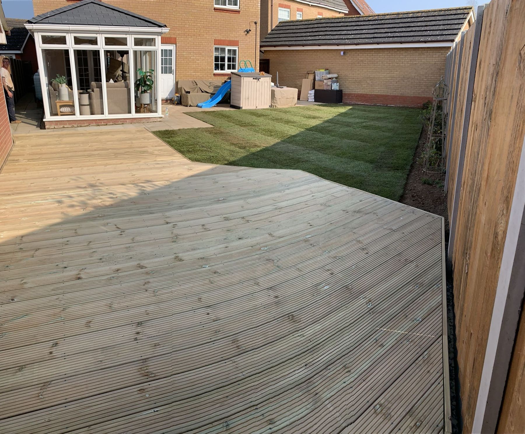 Timber decking outside a conservatory with a lawn beyond