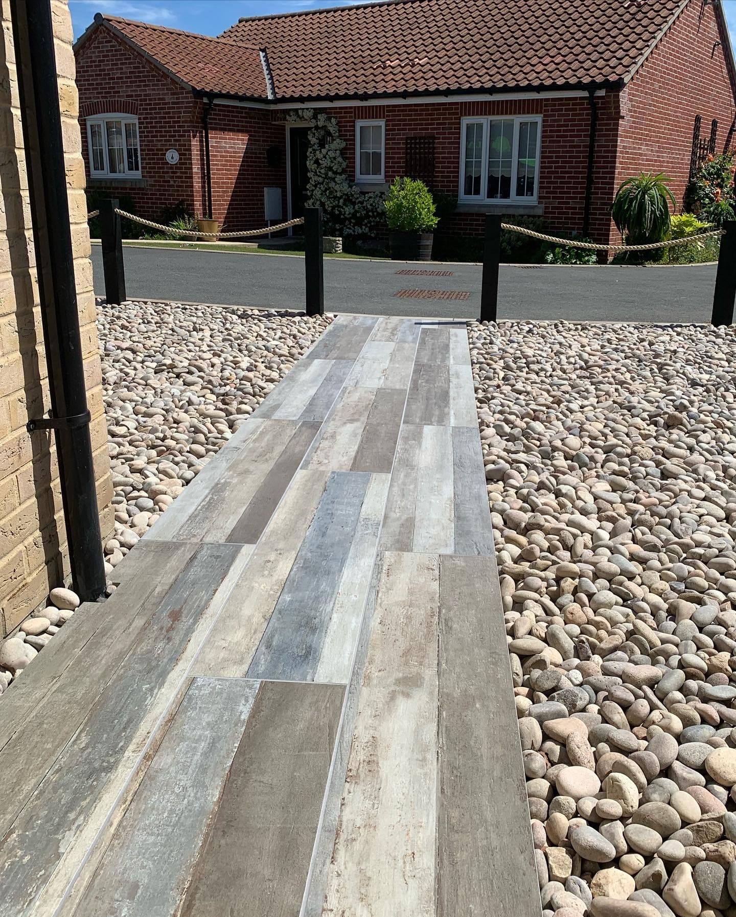 Wood-effect porcelain path through a bed of cobbles